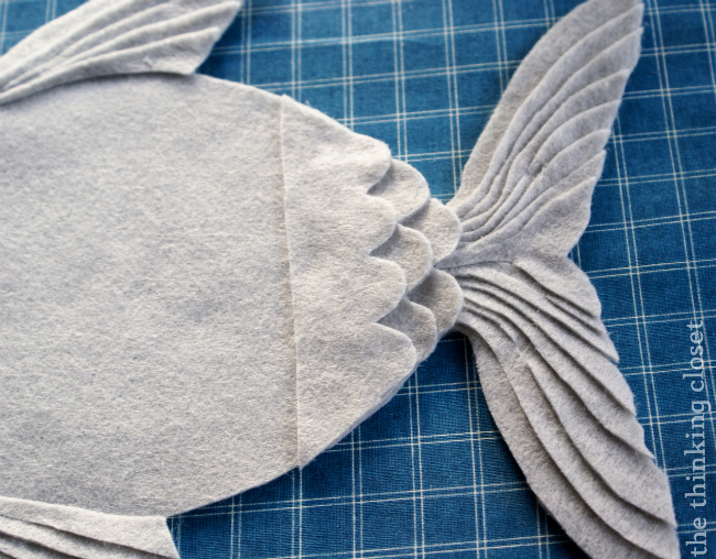 Layering strips of scales to complete a nautical felt fish pillow! via thinkingcloset.com