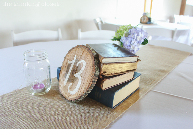 Creative centerpiece idea for a rustic vintage wedding: wood slice table numbers, a stack of vintage books, and mason jars filled with flowers and candlelight. Oh, and let's not forget the burlap table runners! Creative centerpiece idea for a rustic vintage wedding: wood slice table numbers, a stack of vintage books, and mason jars filled with flowers and candlelight. Oh, and let's not forget the burlap table runners!