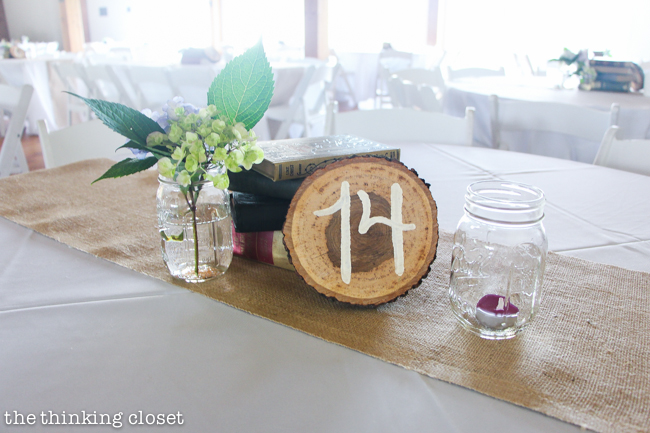 Creative centerpiece idea for a rustic vintage wedding: wood slice table numbers, a stack of vintage books, and mason jars filled with flowers and candlelight. Oh, and let's not forget the burlap table runners! Creative centerpiece idea for a rustic vintage wedding: wood slice table numbers, a stack of vintage books, and mason jars filled with flowers and candlelight. Oh, and let's not forget the burlap table runners!