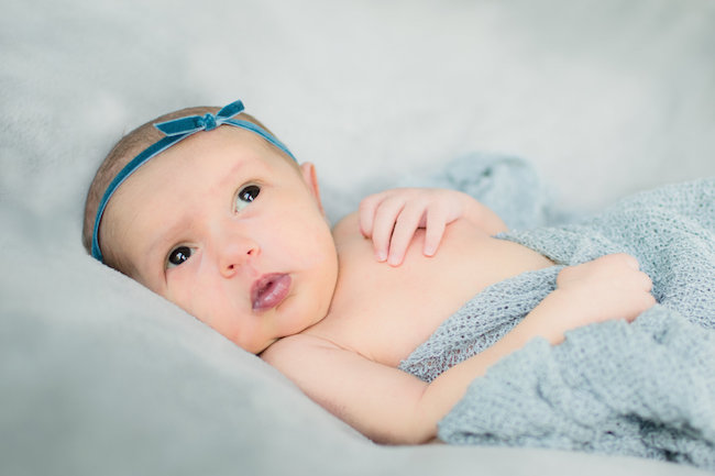 Juniper's 2 week newborn photography shoot: adorable hair bows, muslin swaddles, and a sweet smiling baby in a bucket. Brace yourself for the cuteness!