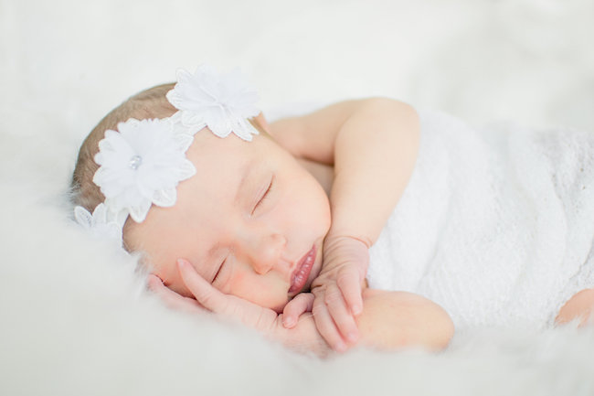 Juniper's 2 week newborn photography shoot: adorable hair bows, muslin swaddles, and a sweet smiling baby in a bucket. Brace yourself for the cuteness!