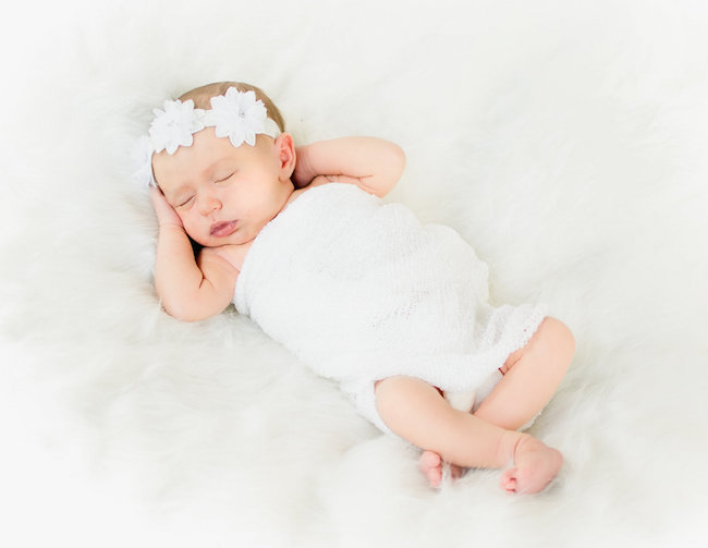 Juniper's 2 week newborn photography shoot: adorable hair bows, muslin swaddles, and a sweet smiling baby in a bucket. Brace yourself for the cuteness!