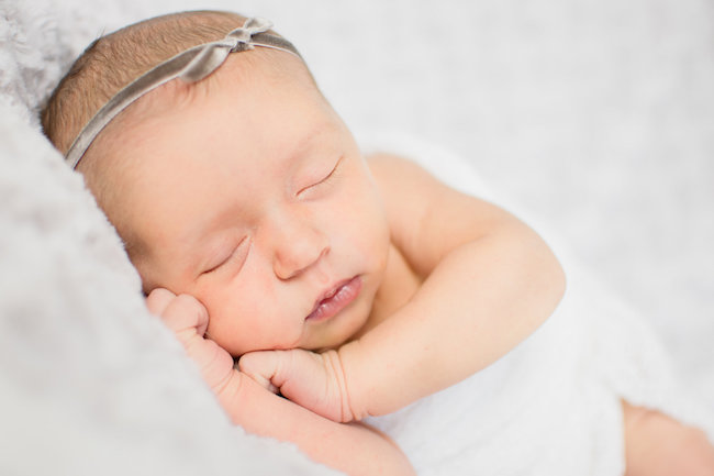 Juniper's 2 week newborn photography shoot: adorable hair bows, muslin swaddles, and a sweet smiling baby in a bucket. Brace yourself for the cuteness!