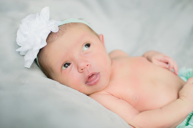 Juniper's 2 week newborn photography shoot: adorable hair bows, muslin swaddles, and a sweet smiling baby in a bucket. Brace yourself for the cuteness!