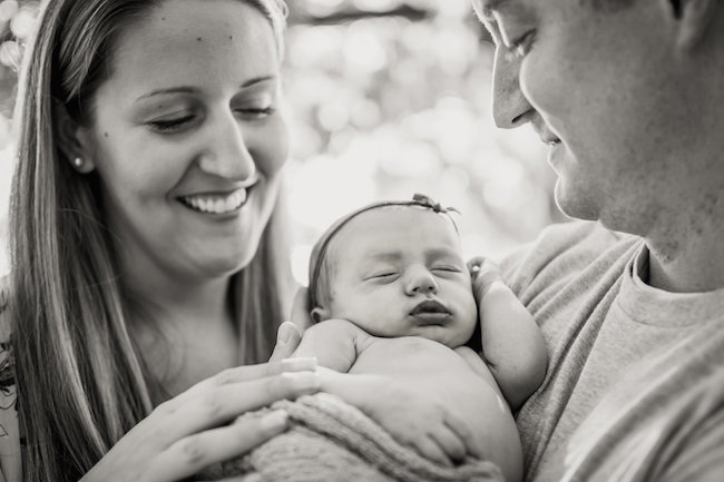 Juniper's 2 week newborn photography shoot: adorable hair bows, muslin swaddles, and a sweet smiling baby in a bucket. Brace yourself for the cuteness!