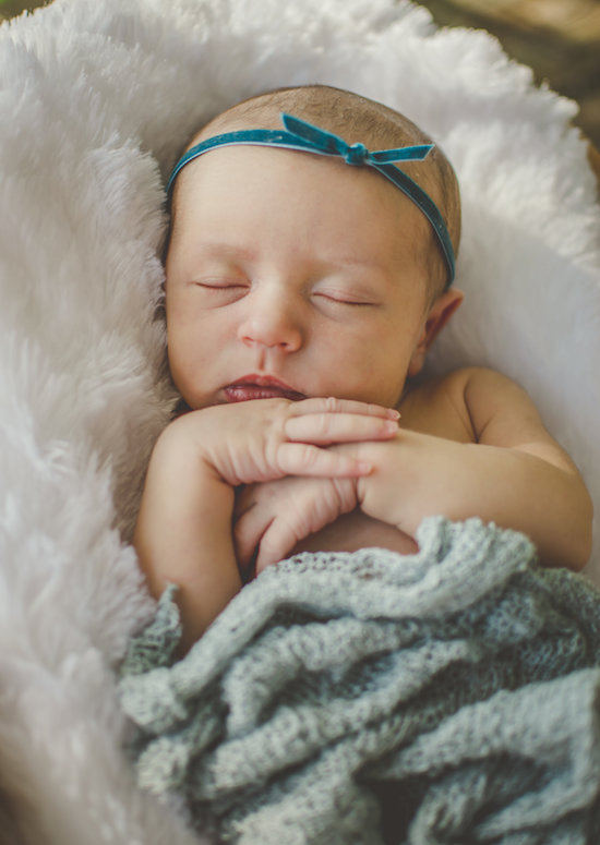 Juniper's 2 week newborn photography shoot: adorable hair bows, muslin swaddles, and a sweet smiling baby in a bucket. Brace yourself for the cuteness!