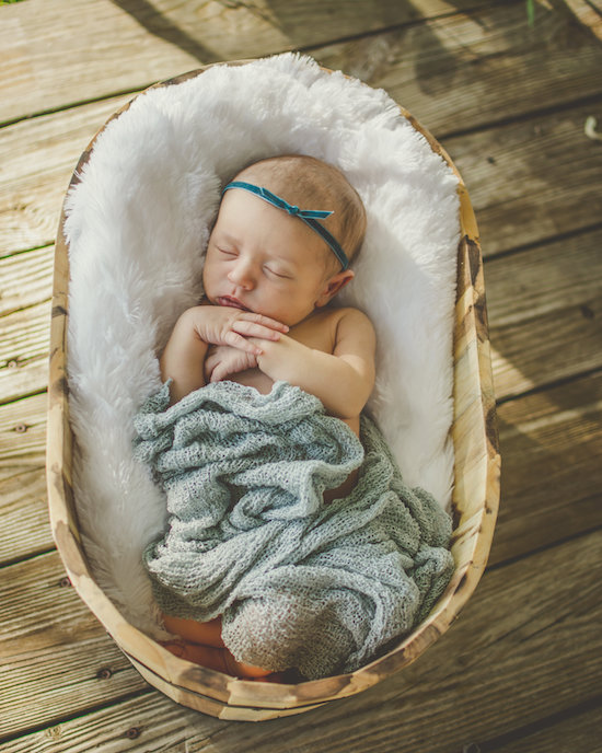 Juniper's 2 week newborn photography shoot: adorable hair bows, muslin swaddles, and a sweet smiling baby in a bucket. Brace yourself for the cuteness!