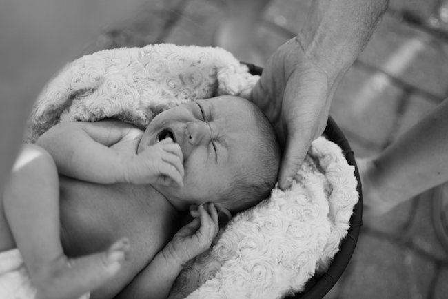 Juniper's 2 week newborn photography shoot: adorable hair bows, muslin swaddles, and a sweet smiling baby in a bucket. Brace yourself for the cuteness!