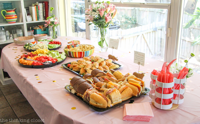 Food platters, mini sign holders, and fresh flowers on display at a Blooming First Birthday Bash, inspired by spring flowers in pink, blush, and white. DIY party ideas for a woodland floral-themed celebration, spring fling, or botanical garden party!