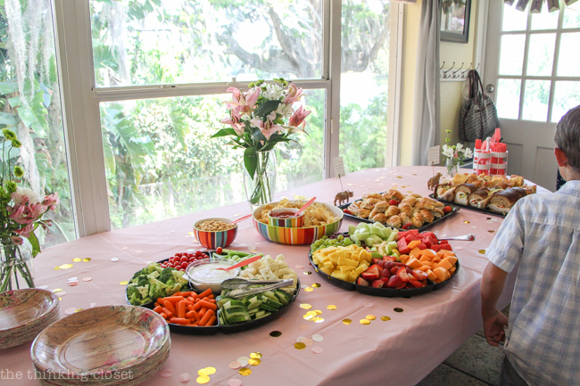 Food platters, mini sign holders, and fresh flowers on display at a Blooming First Birthday Bash, inspired by spring flowers in pink, blush, and white. DIY party ideas for a woodland floral-themed celebration, spring fling, or botanical garden party!