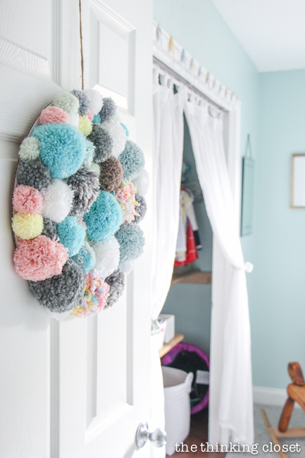 "Little Adventurer" Nursery Tour | An inspirational space with vintage-modern furniture, travel-themed decor, and a gender-neutral color palette of mint, gray, and white. The yarn pom pom wreath on the door is such a fun decor piece!