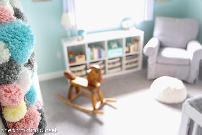 "Little Adventurer" Nursery Tour | An inspirational space with vintage-modern furniture, travel-themed decor, and a gender-neutral color palette of mint, gray, and white. The yarn pom pom wreath on the door is such a fun decor piece!