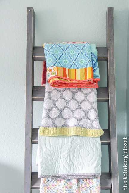 "Little Adventurer" Nursery Tour | An inspirational space with vintage-modern furniture, travel-themed decor, and a gender-neutral color palette of mint, gray, and white. Lovin' this blanket letter as a practical way to store blankets and encourage their use while beautifying the space with their fun patterns!
