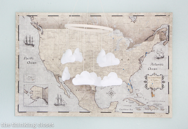 "Little Adventurer" Nursery Tour | An inspirational space with vintage-modern furniture, travel-themed decor, and a gender-neutral color palette of mint, gray, and white. Such a whimsical felt cloud mobile in front of a travel map!