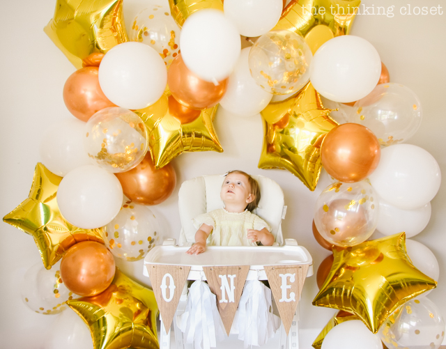 How to make your own balloon garland party backdrop! This white, clear confetti, copper, and gold star balloon banner lasted over a week and took about two hours to complete...well worth it! Check out my post for tips and tricks. | A "Twinkle Twinkle Little Star" 1st Birthday Party, inspired by our favorite baby lullaby. DIY party ideas for a dazzling celebration for your shining star's first birthday or baby shower! via thinkingcloset.com