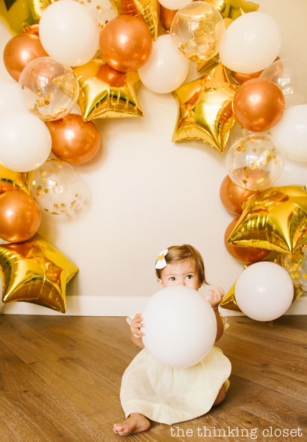 How to make your own balloon garland party backdrop! This white, clear confetti, copper, and gold star balloon banner lasted over a week and took about two hours to complete...well worth it! Check out my post for tips and tricks. | A "Twinkle Twinkle Little Star" 1st Birthday Party, inspired by our favorite baby lullaby. DIY party ideas for a dazzling celebration for your shining star's first birthday or baby shower! via thinkingcloset.com