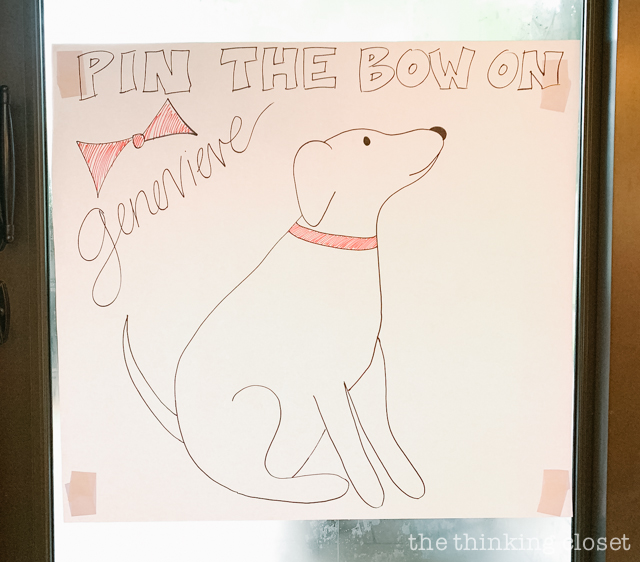 One of our party games was a variation of "pin the tail on the donkey"... this one was "pin the bow on Genevieve," Madeline's dog who rescues her! | How to host a "Madeline In Paris"-themed 4th birthday party at home with creative DIY party activities, French decor, and costumes inspired by the classic Madeline children's books via ThinkingCloset.com