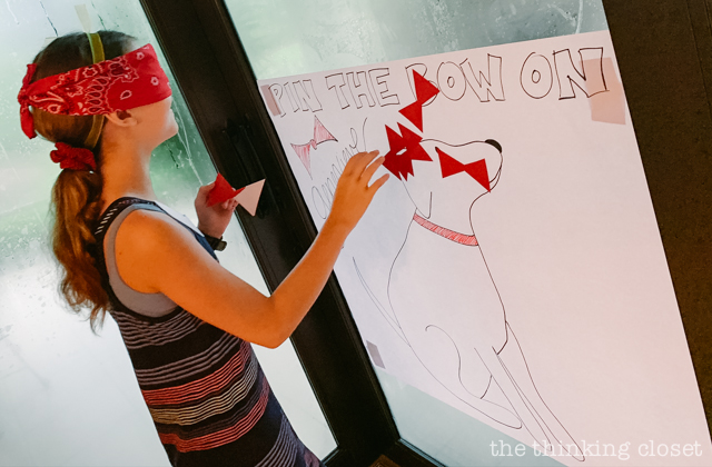 One of our party games was a variation of "pin the tail on the donkey"... this one was "pin the bow on Genevieve," Madeline's dog who rescues her! | How to host a "Madeline In Paris"-themed 4th birthday party at home with creative DIY party activities, French decor, and costumes inspired by the classic Madeline children's books via ThinkingCloset.com