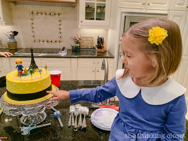 Check out our Madeline-themed birthday cake, decorated to look like Madeline's yellow hat with a satin black ribbon tied around it. Très chic! | How to host a "Madeline In Paris"-themed 4th birthday party at home with creative DIY party activities, French decor, and costumes inspired by the classic Madeline children's books via ThinkingCloset.com